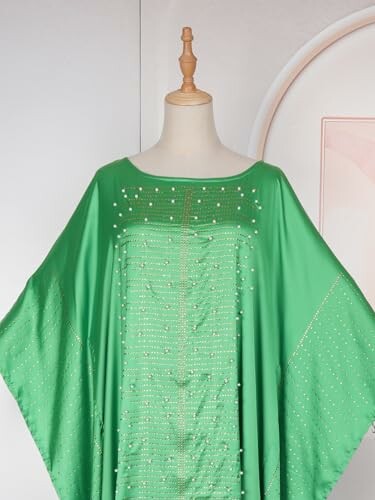 Green kaftan dress with bead detailing on mannequin.